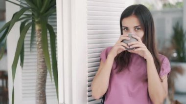 Kahvede poz veren esmer kadının portresi, elinde kahveyle.