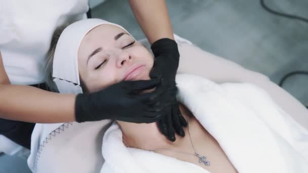 Vista superior de manos esteticistas haciendo masaje facial rejuvenecedor y relajante — Vídeos de Stock