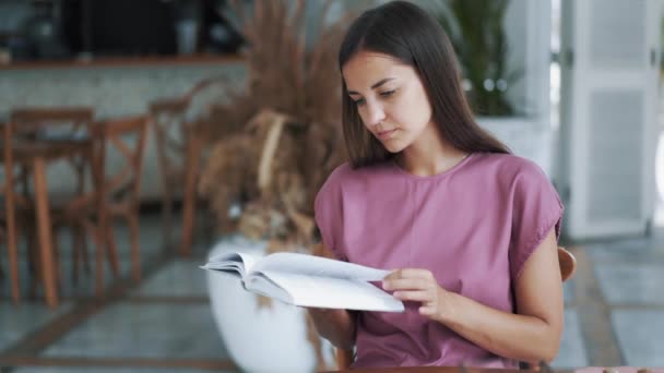 Ritratto di bella donna seduta a tavola nel caffè e libro di lettura — Video Stock