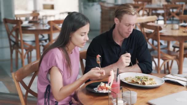 Amantes hombre y mujer sentarse en la cafetería al aire libre, comer alimentos saludables y hablar — Vídeos de Stock