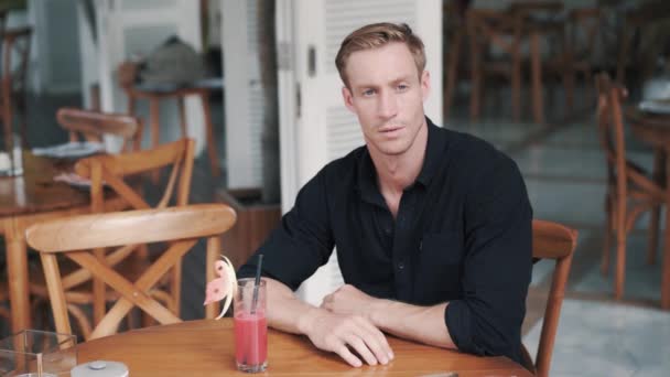 Pensive man sitter i elegant café med nypressad juice och tittar på kameran — Stockvideo