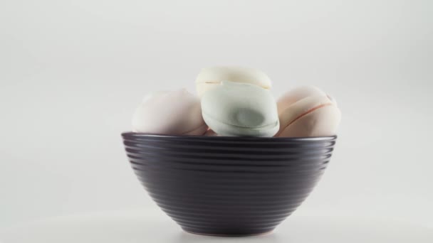 Close-up van gekleurde marshmallows het plaat rotatie over witte achtergrond. — Stockvideo