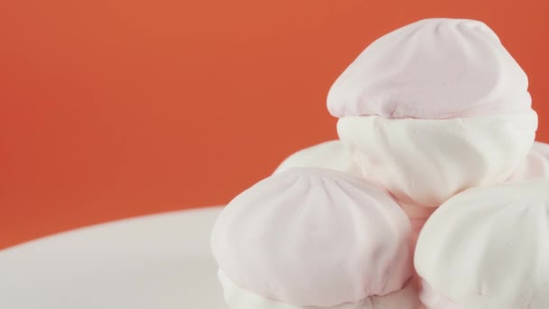 Detailní záběr barevných marshmallows to deska rotace přes oranžové pozadí. — Stock video