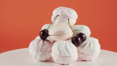 Renkli marşmelov ve kiraz turuncu arka plan üzerinde tabak rotasyonunda. 