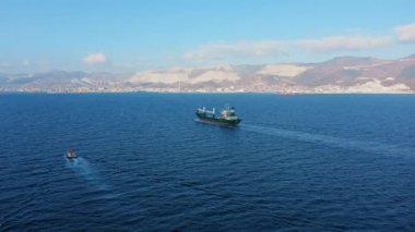 Denizdeki ultra büyük kargo gemisinin hava görüntüsü güneşli bir günde limandan ayrılıyor.
