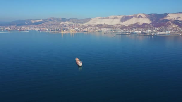 Vue aérienne suivant l'ultra grand cargo en mer quitte le port par temps ensoleillé