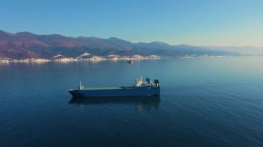 Denizdeki ultra büyük kargo gemisinin yukarıdan aşağı görüntüsü güneşli bir günde limandan ayrılıyor.