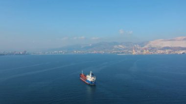 Denizdeki ultra büyük kargo gemisinin yukarıdan aşağı görüntüsü güneşli bir günde limandan ayrılıyor.