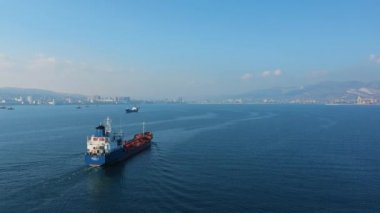 Denizdeki ultra büyük kargo gemisinin yukarıdan aşağı görüntüsü güneşli bir günde limandan ayrılıyor.