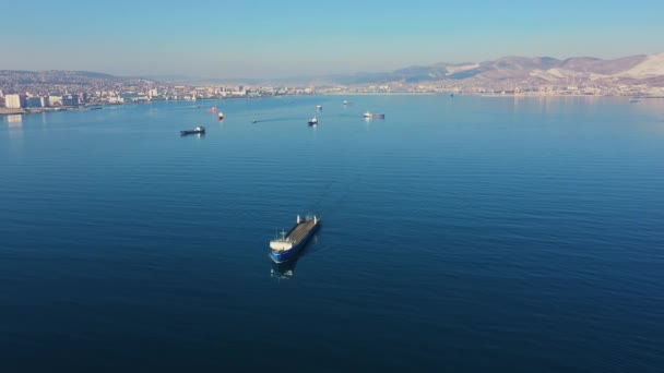 Bovenaanzicht vanuit de lucht op ultragroot vrachtschip op zee verlaat haven op zonnige dag — Stockvideo