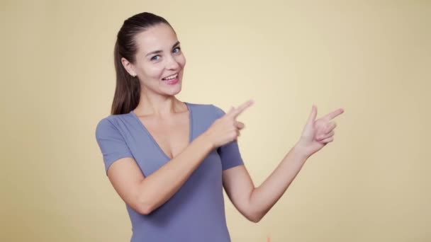 Portrait of woman pointing fingers on something, isolated on beige background — Stock Video