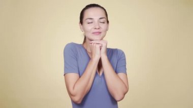 Kız güzel bir yüz yapıyor, güzel bir şeyin hayalini kuruyor, bej arka planda izole edilmiş.