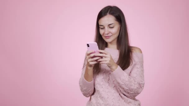 분홍색 스웨터를 입은 여성의 사진, 분홍색 배경에 고립 된 휴대 전화를 사용하는 여성 — 비디오