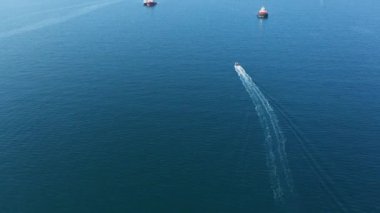 Büyük gemiler arasında mavi denizde küçük teknelerin havadan görünüşü