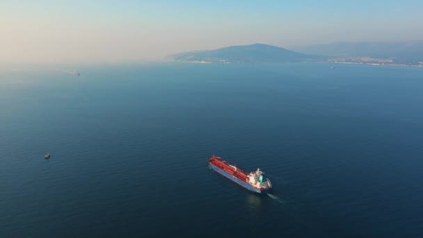 Luchtfoto van een groot vrachtschip dat op zonnige dag de zeehaven verlaat — Stockvideo