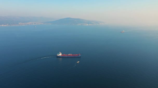 Luchtfoto van een groot vrachtschip dat op zonnige dag de zeehaven verlaat — Stockvideo