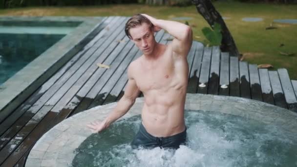 Sexy mužský model se sportovním tělem pózující ve vířivce, zpomalený pohyb — Stock video