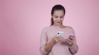 Kadın elinde iki tane akıllı telefon tutuyor ve telefona cevap veriyor.