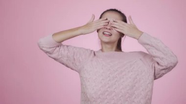 Komik, genç, neşeli kadın elleriyle gözlerini kapar ve gülümser.