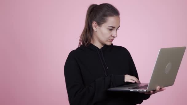 Fiatal fehér barna nő fekete kapucnis tartja laptop — Stock videók