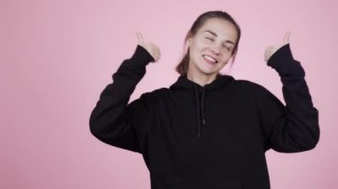 Pembe arka planda poz veren güzel, pozitif dans eden genç bir kadın. 