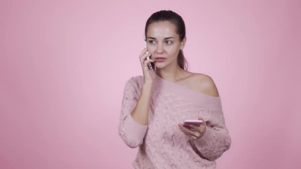 Jonge mooie vrouw manager neemt beurtelings praten op twee smartphones met klanten — Stockvideo