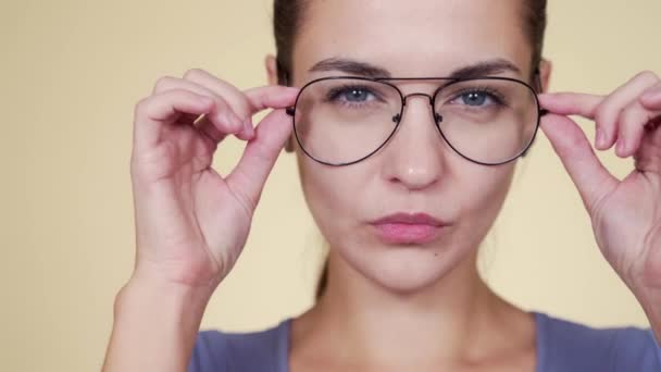 Közelkép egy gyönyörű fehér fiatal nőről, aki szemüveget próbál fel. — Stock videók