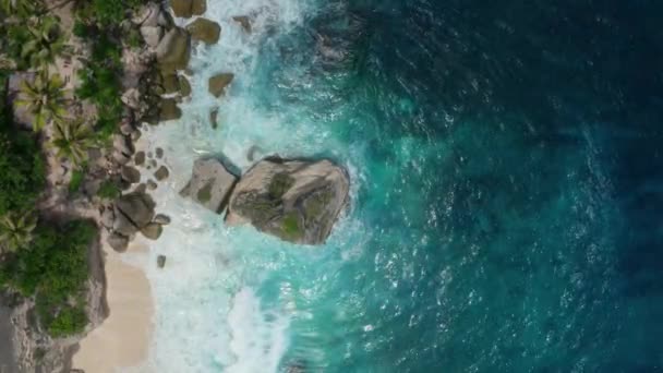 Veduta aerea del drone che si avvicina alla spiaggia con massi ricoperti di vegetazione — Video Stock