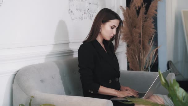 Πλευρική άποψη της όμορφης λεπτής νεαρής γυναίκας που εργάζεται εξ αποστάσεως χρησιμοποιώντας ένα φορητό υπολογιστή — Αρχείο Βίντεο