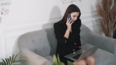 Kendinden emin, beyaz, genç esmer kız müşterileriyle telefonda konuşuyor. 