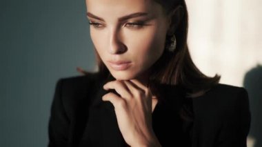 Parlak makyajlı esmer kadın stüdyoda poz veriyor.