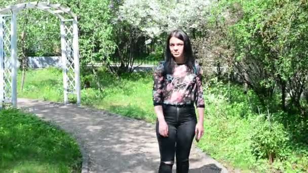 Belle jeune femme en promenade dans le parc du printemps — Video