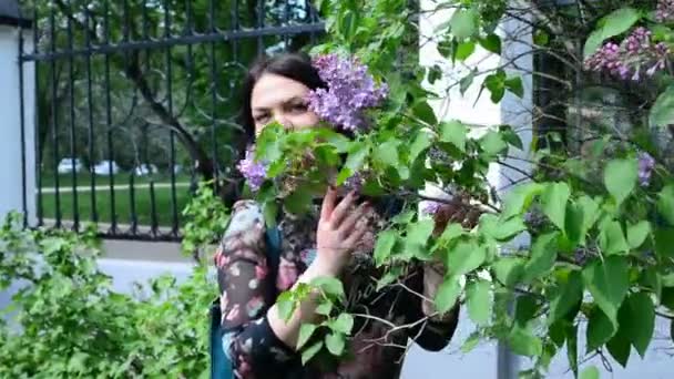 Mooie vrouw wandelingen in het park onder de Lila — Stockvideo