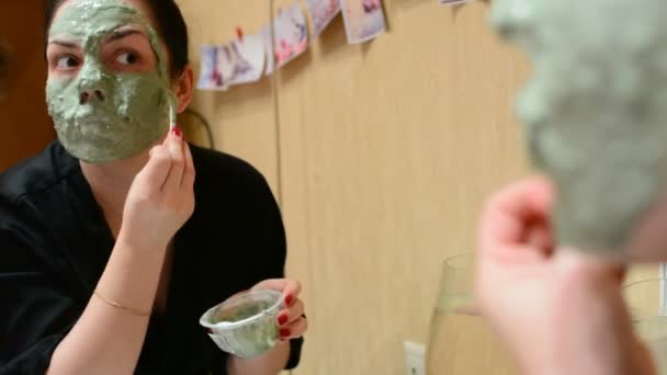 Ung Flicka Tillämpa Kosmetiska Mask Blå Lera Rummet Framför Spegeln — Stockvideo