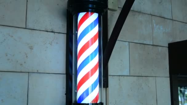 Poste de peluquería girando en la pared en la peluquería. El poste de barbero girando en la barbería. Barbería vintage y el símbolo de peluquería. Polo de peluquería tradicional girando en la barbería — Vídeos de Stock