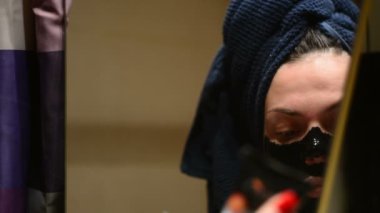 Bir kadın profesyonel kozmetik siyah bir maske kullanarak yüz cilt sonra görünüyor. Temizlik, siyah bir maske ile gözenekleri cilt.
