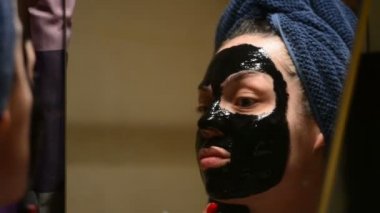 Bir kadın profesyonel kozmetik siyah bir maske kullanarak yüz cilt sonra görünüyor. Temizlik, siyah bir maske ile gözenekleri cilt.