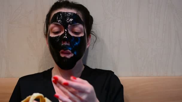 Mädchen Mit Schwarzer Maske Auf Dem Gesicht Isst Bananen — Stockvideo