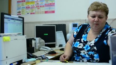 İşçisi kadın Asansör bakım bölümü kontrol odasında üzerinde konuşuyor. Orada birkaç monitörler ve bir telefon.