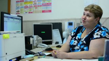 İşçisi kadın Asansör bakım bölümü kontrol odasında üzerinde konuşuyor. Orada birkaç monitörler ve bir telefon.