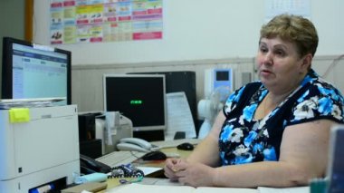İşçisi kadın Asansör bakım bölümü kontrol odasında üzerinde konuşuyor. Orada birkaç monitörler ve bir telefon.
