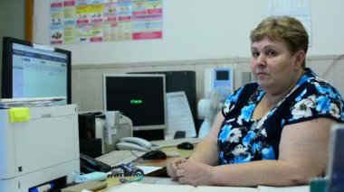 İşçisi kadın Asansör bakım bölümü kontrol odasında üzerinde konuşuyor. Orada birkaç monitörler ve bir telefon.