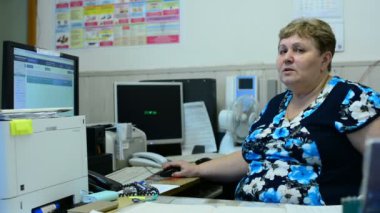 İşçisi kadın Asansör bakım bölümü kontrol odasında üzerinde konuşuyor. Orada birkaç monitörler ve bir telefon.