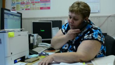 İşçisi kadın Asansör bakım bölümü kontrol odasında üzerinde konuşuyor. Orada birkaç monitörler ve bir telefon.