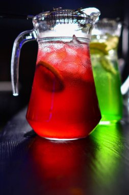 İki cam sürahilere, carafes, portakal ve meyve lemonde üzerinde siyah bir arka plan ile ahşap bir masa ile kök birası alabilir miyiz