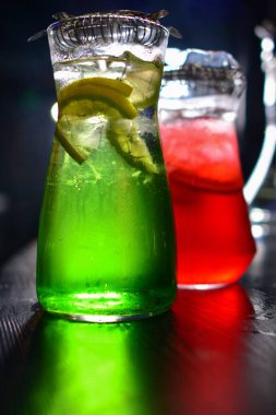 İki cam sürahilere, carafes, portakal ve meyve lemonde üzerinde siyah bir arka plan ile ahşap bir masa ile kök birası alabilir miyiz