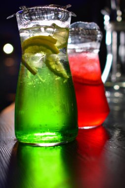 İki cam sürahilere, carafes, portakal ve meyve lemonde üzerinde siyah bir arka plan ile ahşap bir masa ile kök birası alabilir miyiz