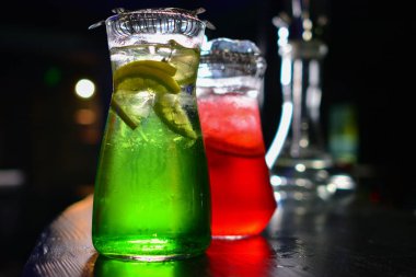 İki cam sürahilere, carafes, portakal ve meyve lemonde üzerinde siyah bir arka plan ile ahşap bir masa ile kök birası alabilir miyiz