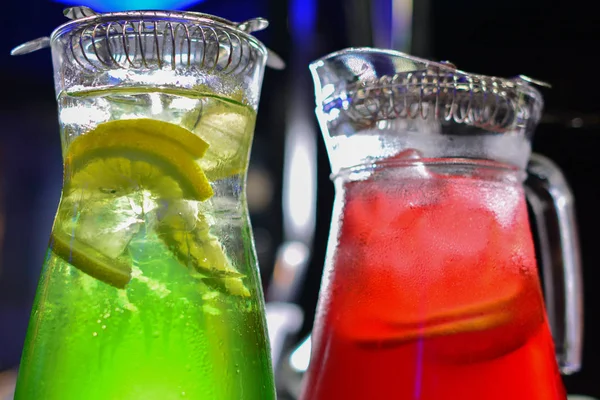 İki cam sürahilere, carafes, portakal ve meyve lemonde üzerinde siyah bir arka plan ile ahşap bir masa ile kök birası alabilir miyiz