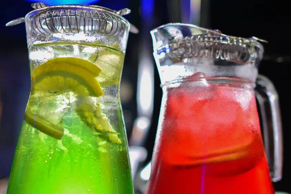 İki cam sürahilere, carafes, portakal ve meyve lemonde üzerinde siyah bir arka plan ile ahşap bir masa ile kök birası alabilir miyiz